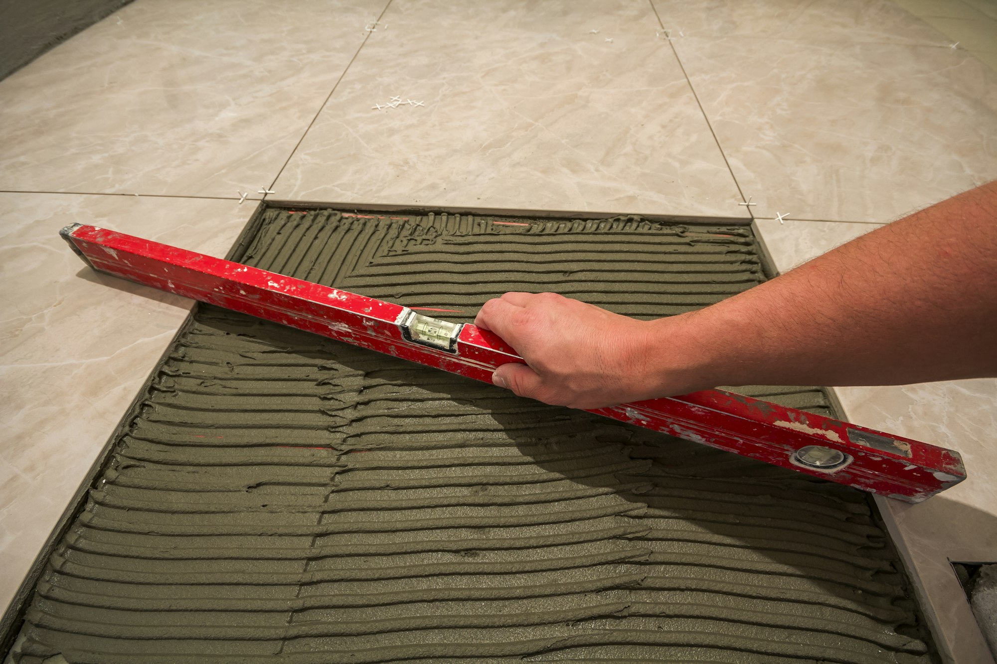 Ceramic tiles and tools for tiler. Worker hand installing floor tiles.