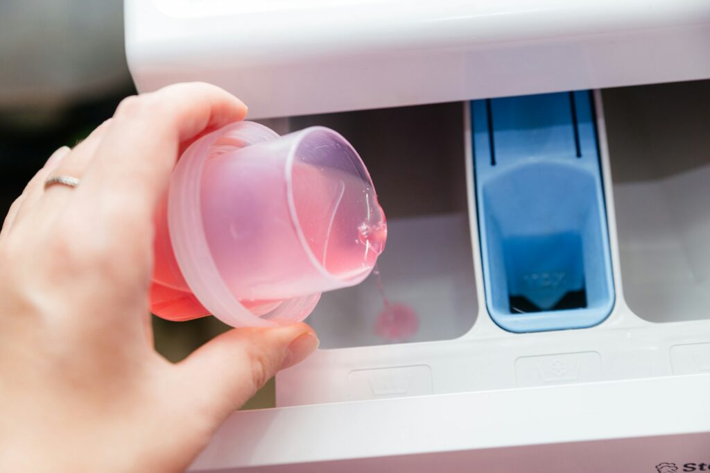 Close-up of a woman's hand pouring laundry detergent into a washing machine