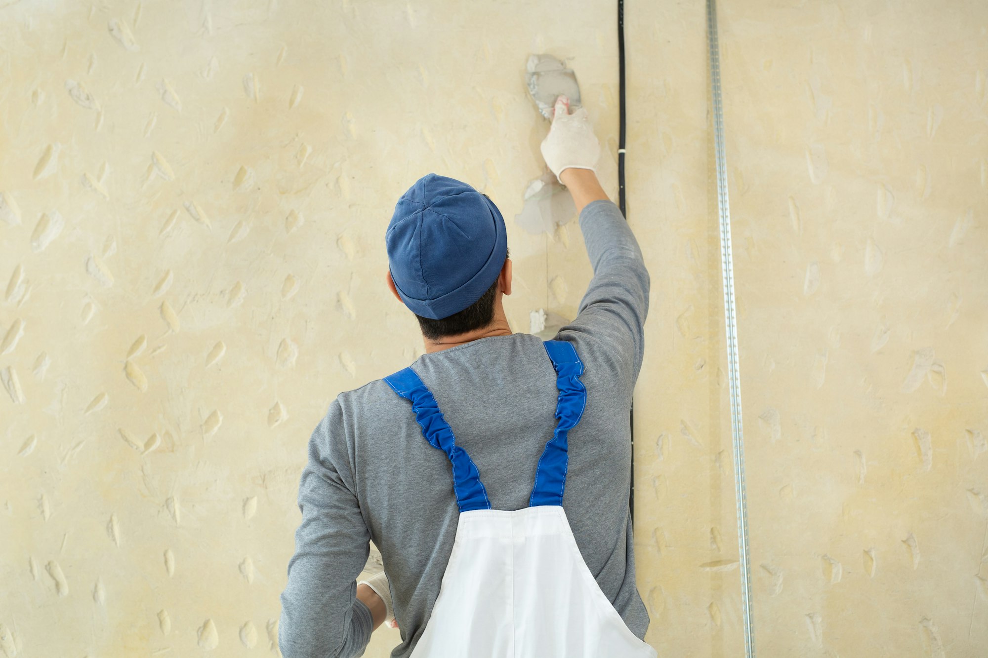 A hand with a spatula. Workers put putty on the wall with a spatula. Aligns wall.