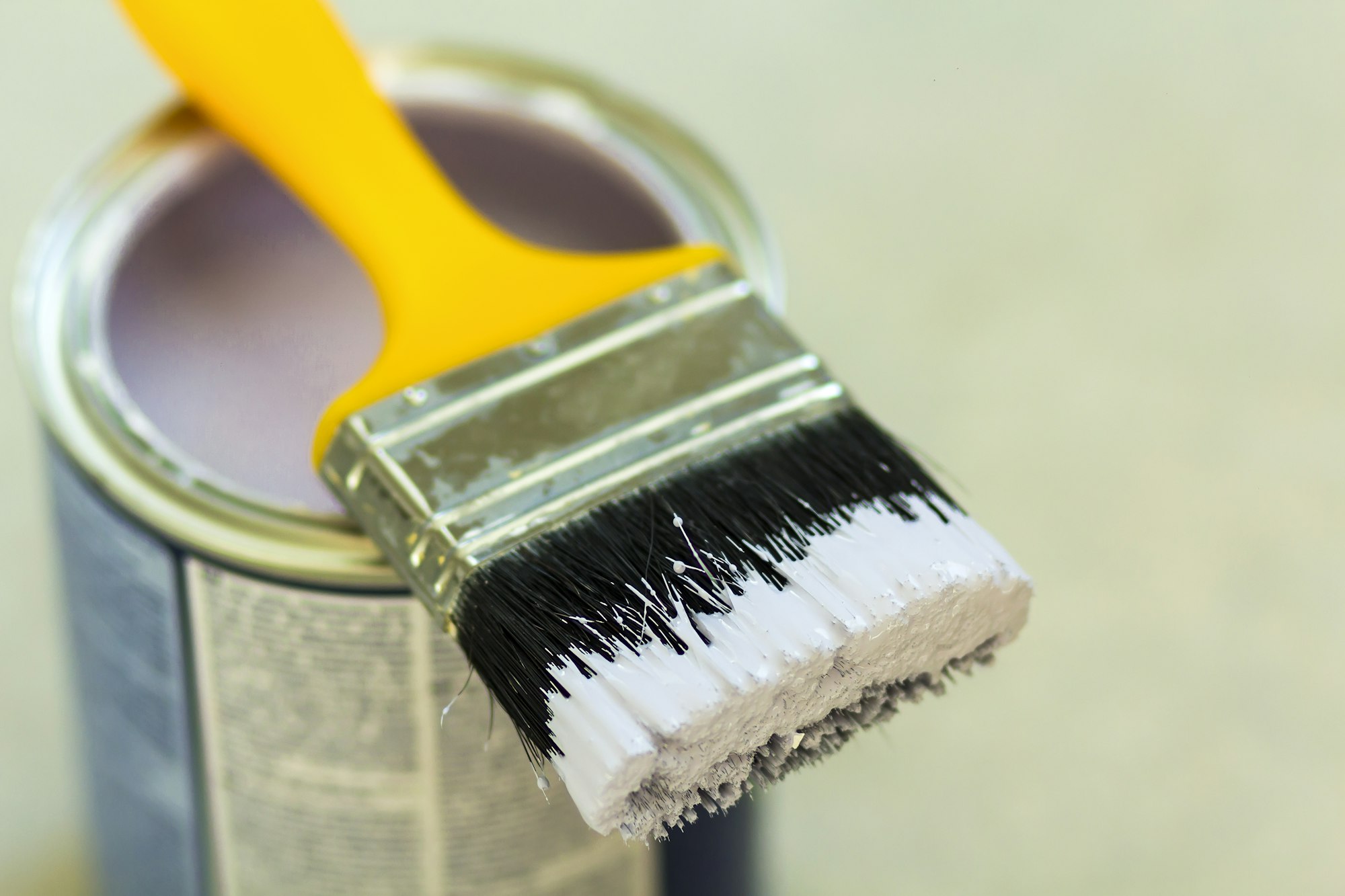 Can of white paint with paint brush over grey background. Shallow depth of field effect