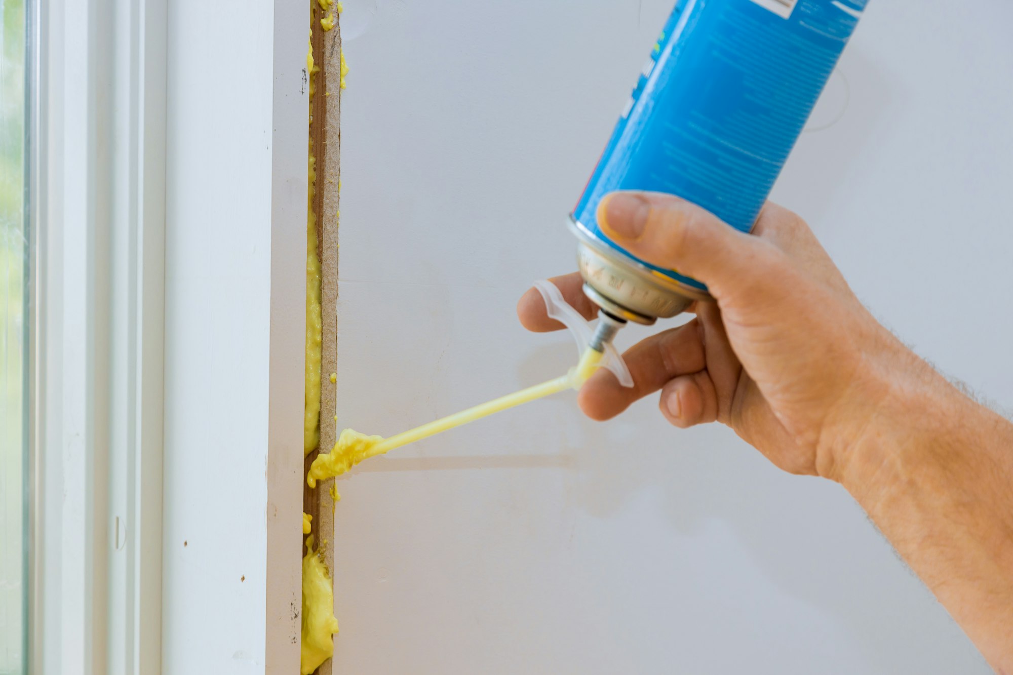 Construction foam is blown into gap between window wall by a worker