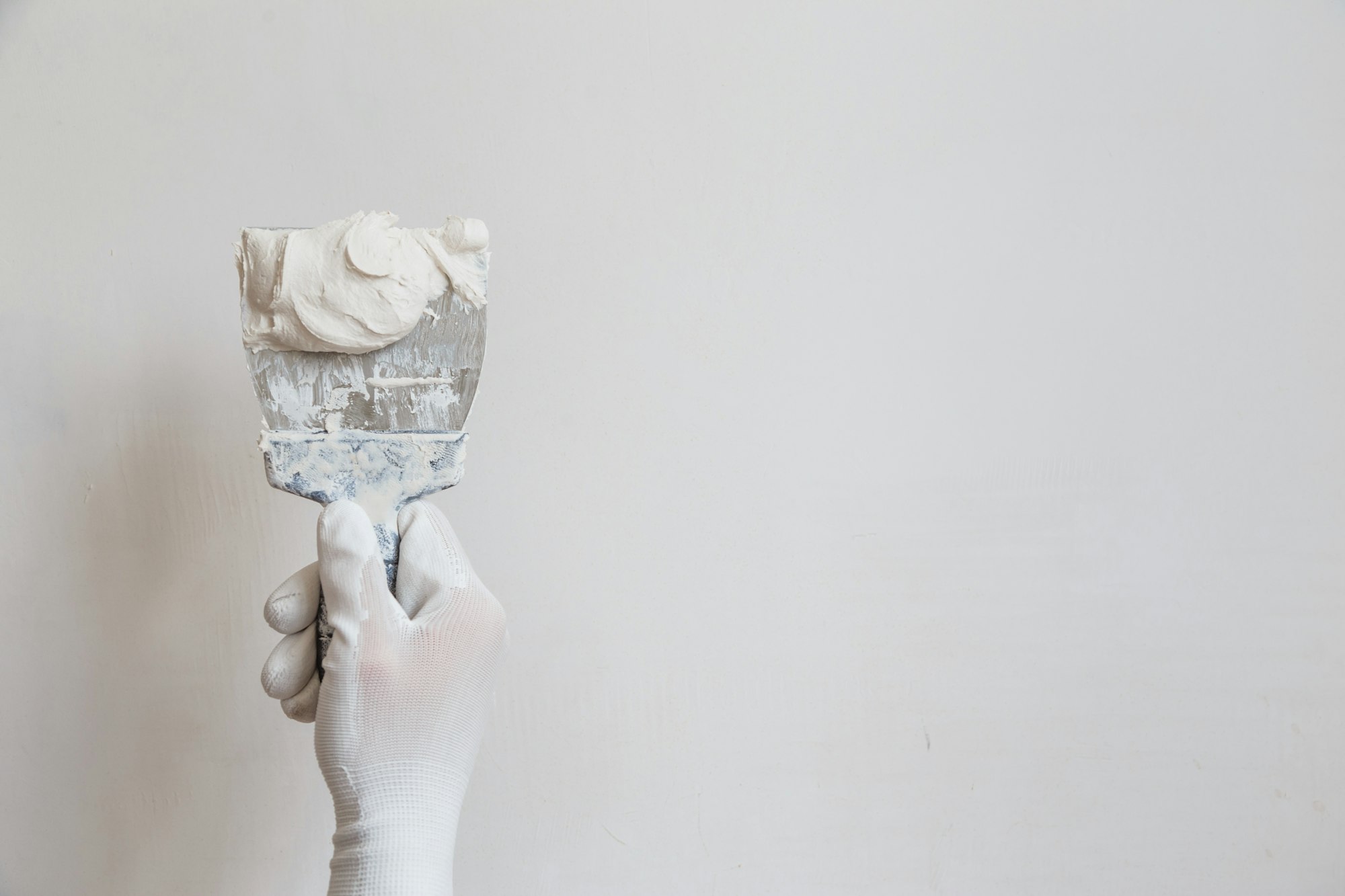 Worker in white gloves performs plastering of the walls of the room