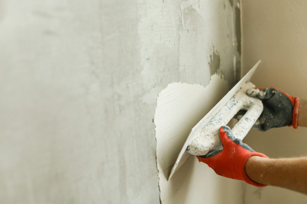 Worker plastering walls with gypsum plaster and spatula