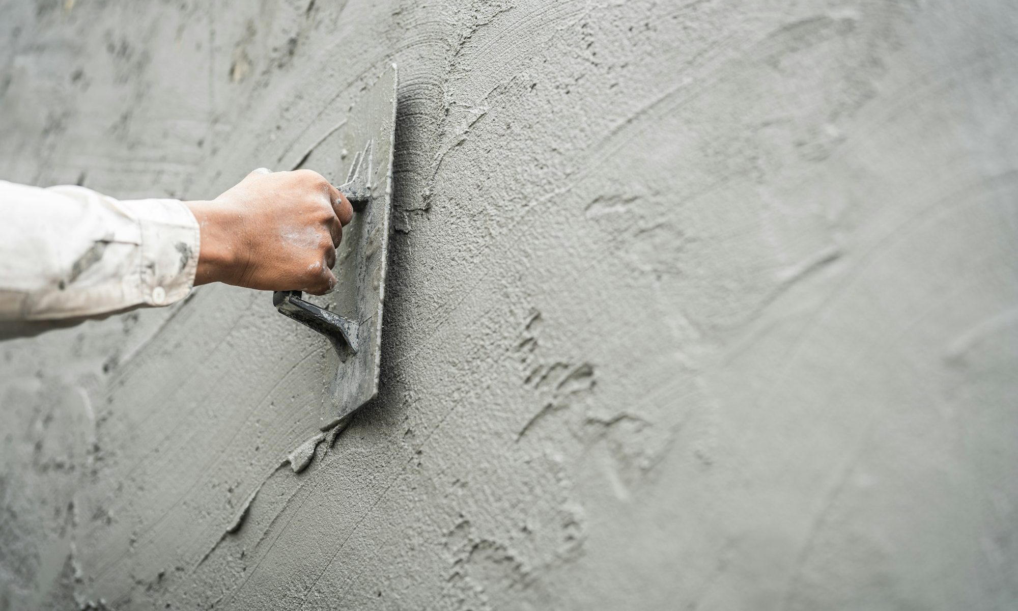 Hand worker plastering cement wall with rough concrete for smooth building wall well free space