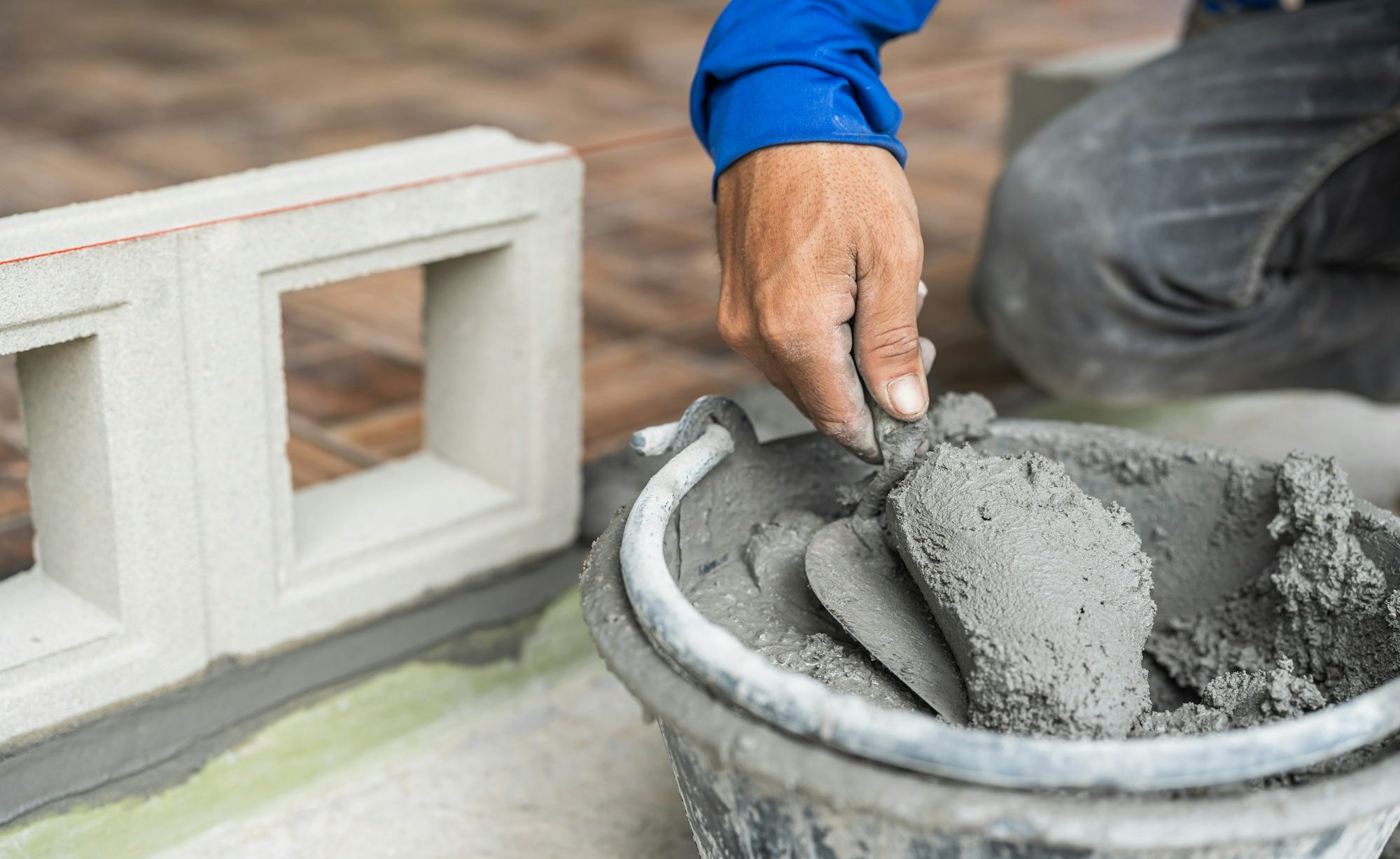 Hand worker with trowel wet cement bucket for masonry brick wall